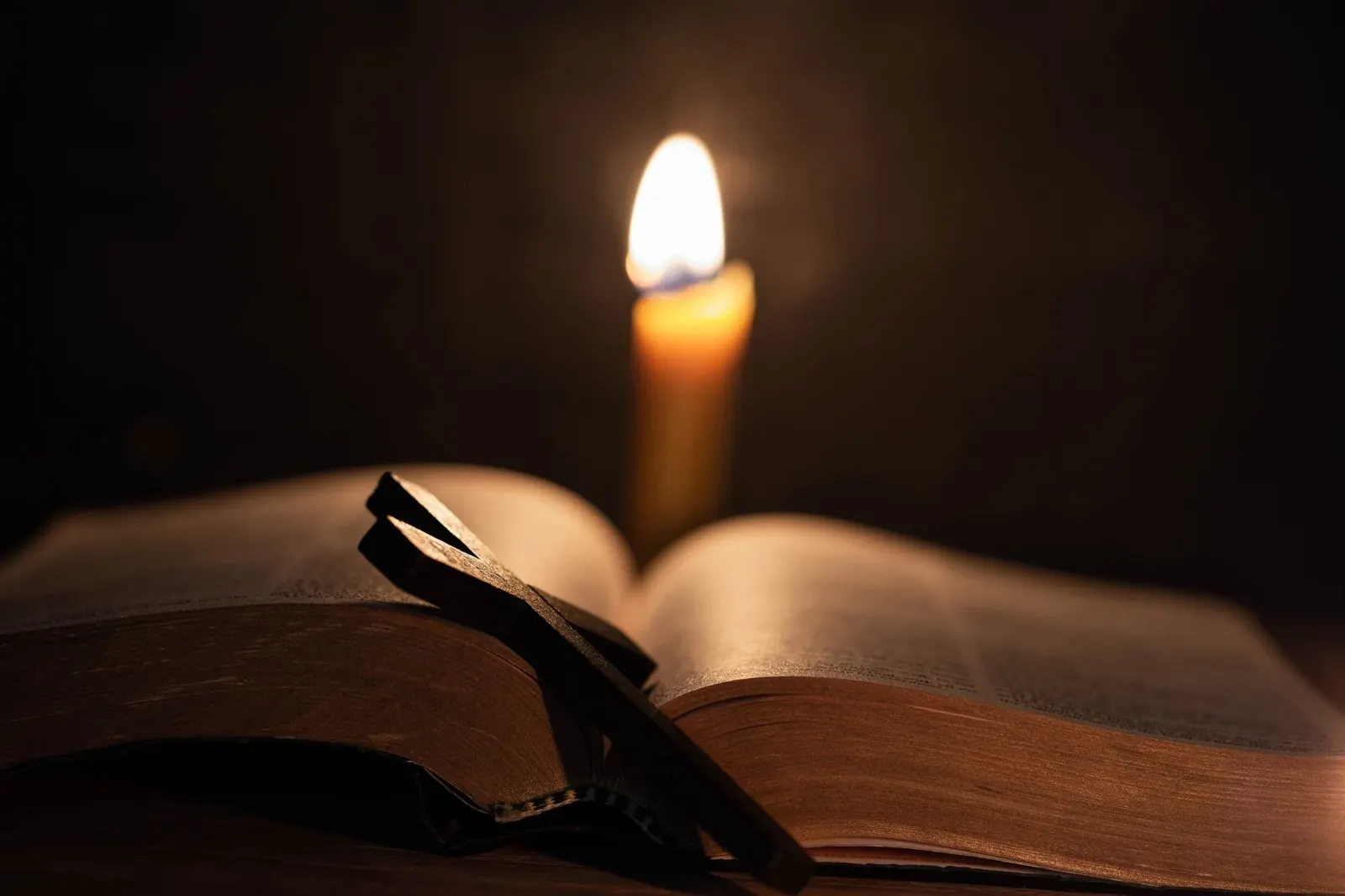 An open Bible lit by a candle